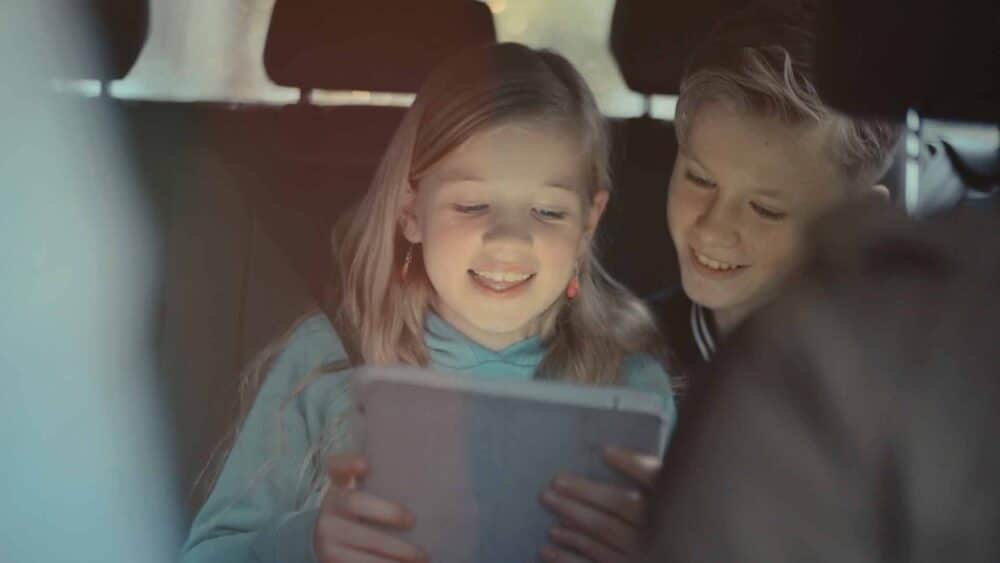 Twee kinderen achterin de auto met een tablet